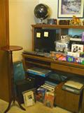 Computer desk, computer, candle stand, beautiful black glove on top of desk and lots of miscellaneous bags and boxes of computer accessories.
