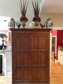 Nicer, vintage wooden storage armoire/Linen press, with just-in-time for Thanksgiving pheasant feather urn doo dads, pair of metal blackbirds, pair of vintage galvanized tin railroad lanterns and a happy cast iron Nipper dog.