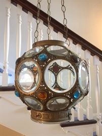 Fantastic antique hanging globe with beveled glass roundels and colored glass jewels, all set in decorative brass or bronze framework. Recently cleaned and restored by Adams Electric of Wilmette. Illuminated by four small electric light bulbs located in the base. With extra-long chain/cord, for suspending in a spacious atrium. Hanging in the front hallway area.  