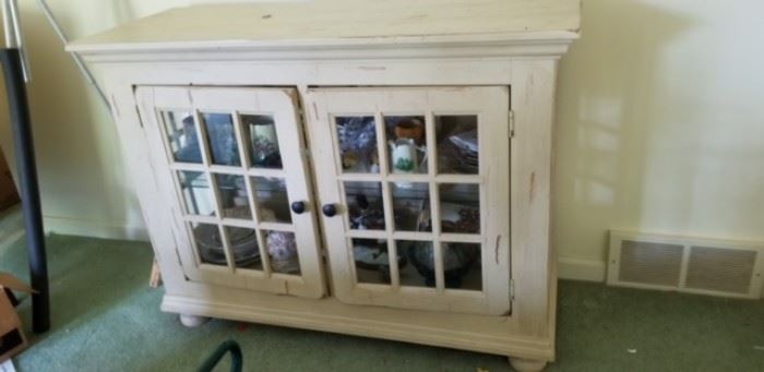 Contemporary cabinet with glass shelves and bun feet; actually more of a cream paint color than this white.