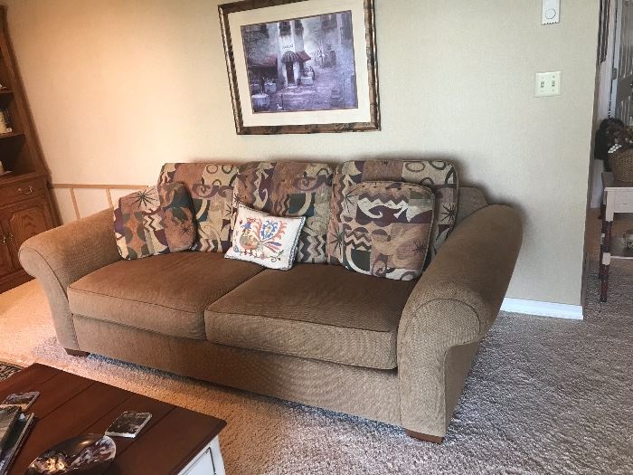 Loveseat in neutral tone with decorative pillows. 