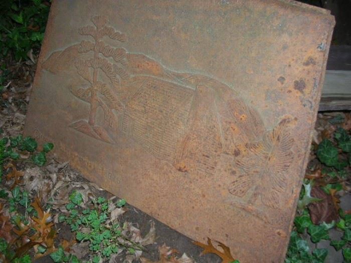 Iron stove door with log cabin and trees