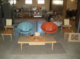 Basement:  Two individually priced mid-century modern saucer chairs (as is) with tapered walnut legs are paired with a set of two 1950's blonde step-back tables.  Also shown is a separately priced blonde coffee table which has one drawer.  In between the two saucer chairs is a bird cage which comes with some accessories and there different cloth covers. 