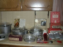 Kitchen:  A large selection of like-new GUARDIAN-WARE cookware is available.  There is even one set of black handles that can be used on any of the pieces.  Also shown is a vintage GUARDIAN-WARE cookbook.  To the right are vintage:  General Mills/Betty Crocker "Tru-Heat Iron" in its original box; a General Mills/Betty Crocker "Steam Iron Attachments" in their original box; GENERAL ELECTRIC vintage refrigerator accessories: glass drawer and aluminum "mini cube" ice cube trays; and a red plastic rocket-shape DAZY ice crusher model 160.  