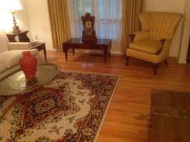 Living Room:  The opposite side of this room has a like-new vintage drop-leaf coffee table with leather top and two drawers.  It matches the side tables.  On it is an antique pressed wood clock (Citizen No. 18, manufactured by Wm. L. Gilbert Clock Co., Winsted, Conn., USA). The vintage gold channel back chair with carved kegs is by Famous-Barr; and the Kirman pattern olefin rug (with pad) measures 5'  7" X 8'  3."