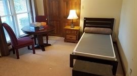 Twin bed with low profile box springs and memory foam mattress, cherry toned table and two burgundy upholstered chairs