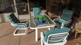 Glass top patio table with four rocker chairs