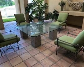Lux patio set. Iron work chairs and cushions. Heavy beveled glass top table on concrete pillars. 