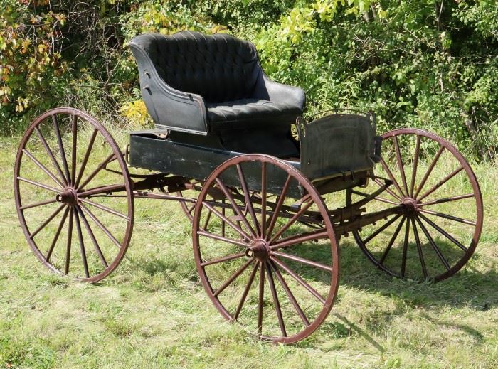 A turn of the century one horse open Carriage.  Open top with single black tufted leather seat.  Lacking canopy/cover; modified and marriage piece (chassis has been adapted for a motor), lacking shafts, repainted portions, losses to leather, paint, etc..  Approximately 62" h, 64" w, 102" long.  