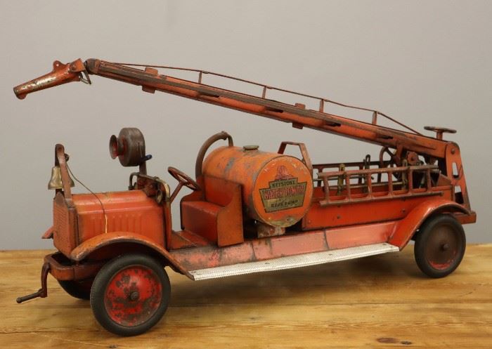 A 1920's Keystone Pressed Steel Fire Truck.  Painted red with original decals.  Significant wear, water tank loose.  33" long overall. 