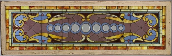 A late 19th century Transom Window.  Multi color glass with clear circular bevels in a painted wood frame.  Some cracks to the panels.  76 3/8" x  24 5/8" high overall. 