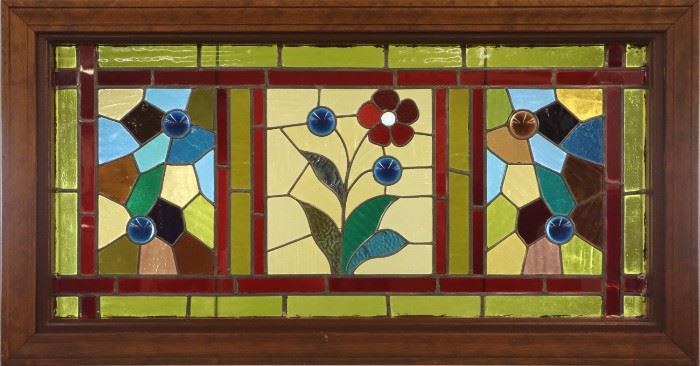 A late 19th century Stained & Leaded Glass Transom Window.  Multi color floral design with cabochon and faceted glass accents in a painted wood frame.  Some cracked panels.  48 1/8" x 25 1/4" high .