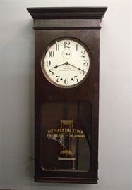 An early 20th century Differential Clock Co. wall clock with 1 year duration.  Robust brass time only movement with dual springs, painted metal dial having Arabic numerals and seconds bit.  Includes the original iron winding crank.  Mahoganized case with original dark finish, single door with "Differential Clock, Runs one year - One winding" in Gold lettering on lower glass.  Original dark finish with wear and some veneer damage.  Running when cataloged.   41 3/4" high.
