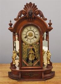 A late 19th century New Haven "Occidental" model shelf clock.  8-day time and strike movement with a painted metal dial.  Walnut case with a carved crest, mirrored sides and cast metal mounts.  Partial paper label on back.  Older finish with some wear, minor dial wear.  Running when cataloged.  24" high overall. 