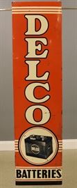A mid 20th century Delco Painted Tin Sign.  Single sided rectangular sign on a wood frame.  Wear with some denting and corrosion.  70 1/2" high overall.  