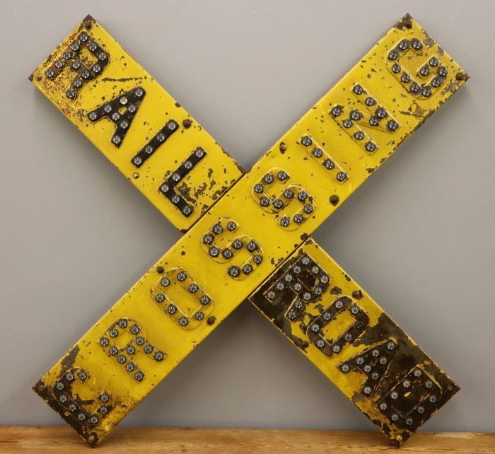 An early to mid 20th century Railroad Crossing Sign.  Yellow painted steel crossbuck sign enhanced with glass cat-eye reflectors.  Wear, losses, and scratches to the paint, some corrosion, missing one glass reflector.  39 1/2" high.