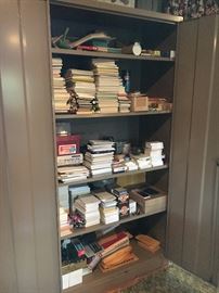 Double door metal cabinet, full of office supplies.