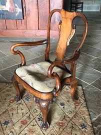 PAIR OF GEORGE I STYLE CARVED WALNUT AND PARCEL-GILTWOOD OPEN ARMCHAIRS                              Early 20th Century                                                                                The yoke crest rail with paper scroll above an inverted baluster splat with gilded leaf and paper scrolls motif within serpentine stiles flanked by shaped arms with shepherd’s-crock hand terminals above a compass seat with seat with drop-in cushion on cabriole legs with shell-carved knees terminating in claw-and-ball feet at front, padded feet at back.