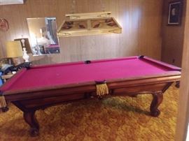 Custom Oak Pool Table by Golden West Billiards with accessories - the rectangular top having a plaque reading "Custom Made by Golden West Billiards, Inc. Los Angeles, CA", surrounding a red or maroon felt playing surface, the rail with leather and scarlet bullion fringe pockets, above shaped paneled sides, the whole rising on cabriole legs, ending in scroll feet. 32" high X 109" wide X 59" deep together with 1 cover, set of balls, cue sticks, racks & cue ball, 