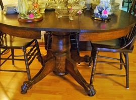 THE MAGNIFICENT ROUND OAK TABLE WITH THOSE BEAUTIFUL FEET.  BEHIND IT IS THE WOODEN CASE WITH 2 LEAVES.  SEE NEXT PIC FOR BOX