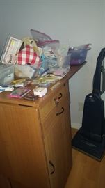 Fold Out Sewing Table on wheels. Drawers & Cabinet on one side and Cabinet on the other. Lots of sewing supplies.