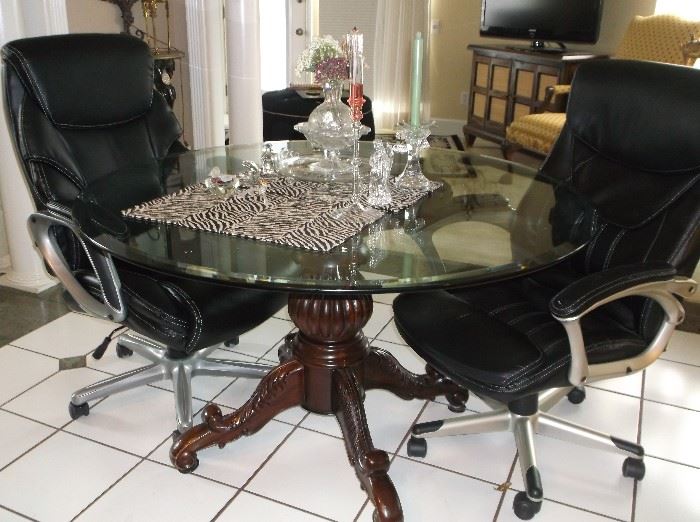 Round glass top ornate mahogany pedestal table and faux leather chairs on casters 