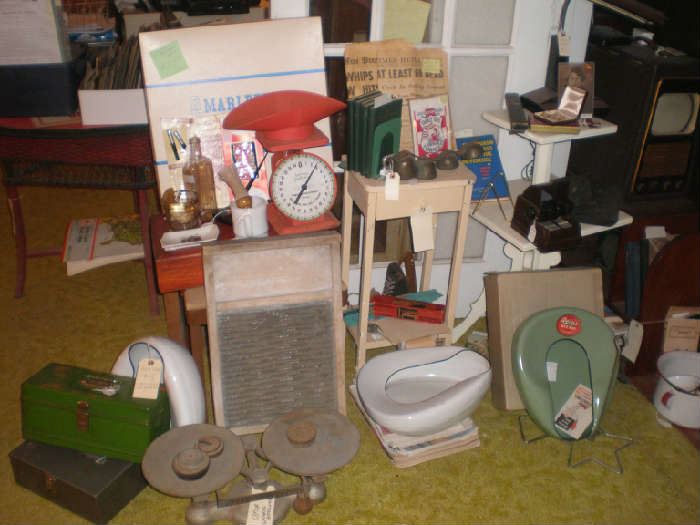 Metal boxes, scales, wash board, bed pans, scales, Marlette businesses game, old newspapers, tiny side table, 2 -tier table.