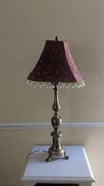 Brass candlestick style lamp with claw feet. Burgandy shade with drop beading. $25.00