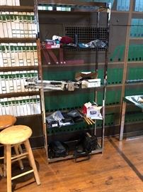 four shelf glass etagere filled with cameras, camcorders, binoculars and more