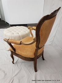 Shield-back leather upholstered armchair.
Button-tufted white upholstered ottoman.