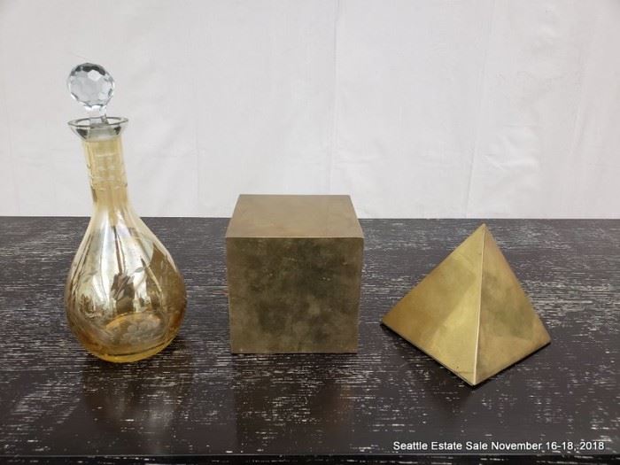 Gold-tone glass decanter and a pair of brass forms.