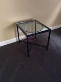 Square with round and square metal base and glass top side table.