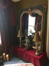 Antique Victorian plaster mirror with guilded trim showcasing a bronze putti and a pair of small Italian lamps