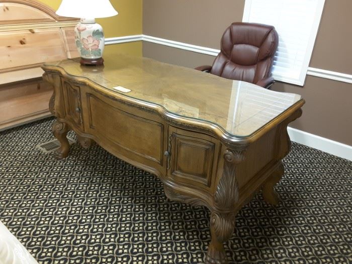 Frontside of executive desk in a light distressed finish. Featured on the front right and left corners are shallow doors with storage space.
