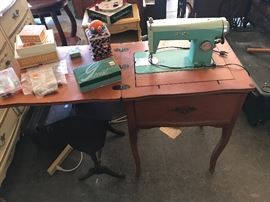 White sewing machine in cabinet with sewing accessories