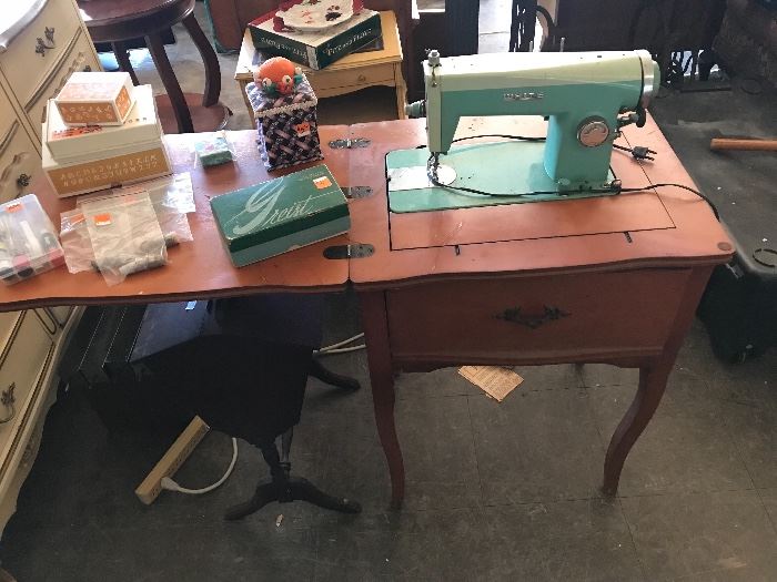 White sewing machine in cabinet with sewing accessories