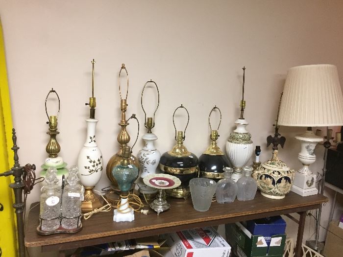 Table full of lamps, 4 bottle Decanter set with porcelain tags, German punch bowl (as is), Verlys vase, 2 etched decanters (as is).