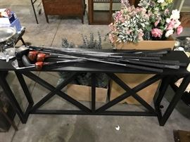 Nice set of golf clubs; black console table or bench (wood).