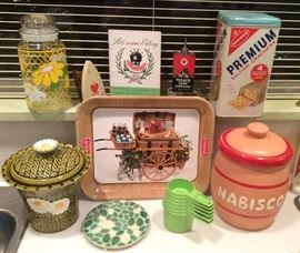 Festive kitchen accessories: floral canisters, Coca Cola tray, Tupperware measuring cups, McCoy Nabisco cookie jar, Premium saltines tin (one of several for sale)
