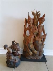 Wood carvings hand carried from Bali and Thailand.  Solid wood carving of the Monkey God holding a ball and a snake from Bali. Fair condition.  Traditional Thai dancers carved from a solid piece of wood on a black stand. Good condition.