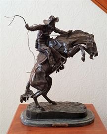High quality mid to late 20th century bronze sculpture after the original entited "Bronco Buster" by Frederic Remington, green marble base, 24" tall, 18" wide, and 12" deep. Also includes a beautifully illustrated coffee table book "Bronzes of the American West".