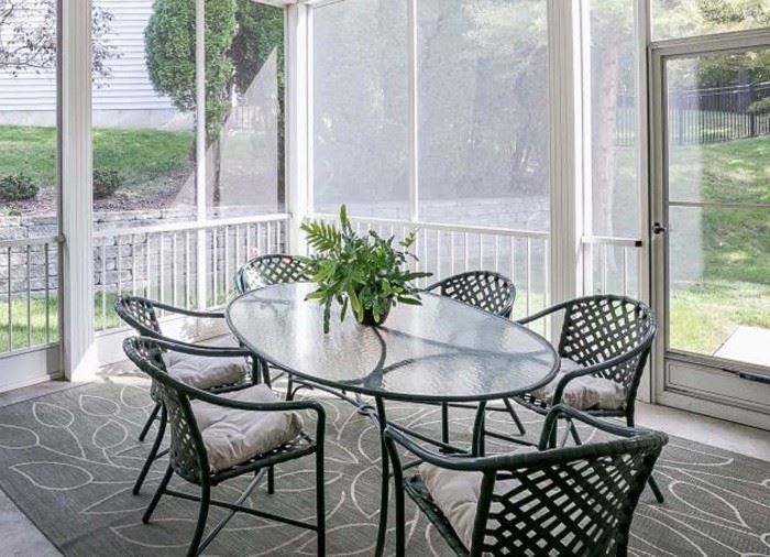 Oval glass top patio table with six armed chairs on the back patio
