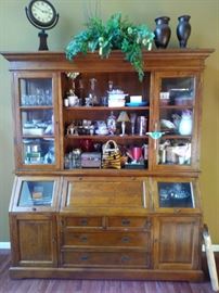 This Stunning  2/pc cabinet (made by Jacques) is in the very large living room just beyond the foyer.  6'6" wide X 8' tall. Featuring 9 shelves above with 2 glass side doors on top + the bottom has 2 slant-top doors, 1 drop-down desktop, 2 doors nestled against a chest of drawers.  Gorgeous!  Beautiful accent to house your pretties! 