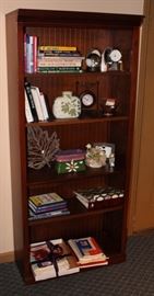 Very nice bookcase with books, knick knacks and sheet music and music books.