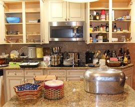The kitchen is full of clean cookware and supplies. Longaberger baskets and large Wagner Ware Magnalite roaster is shown on the island.