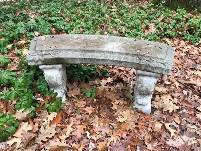 One of a pair of curved cement garden benches 