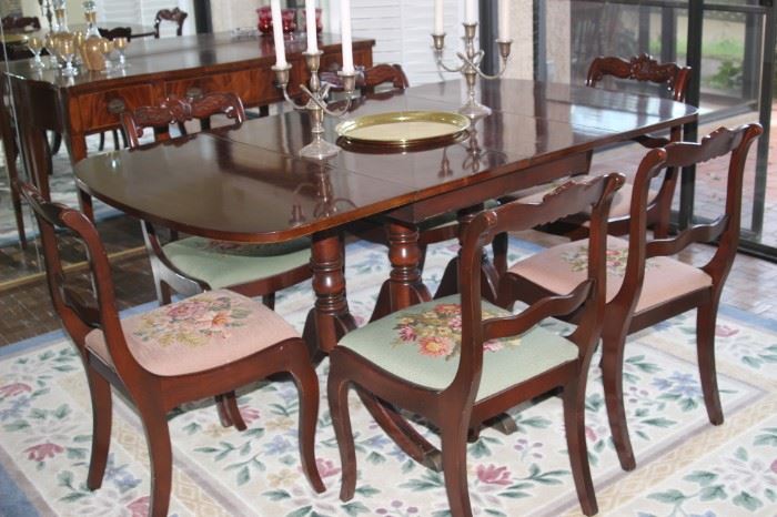 Duncan Phyfe style dining table with leaves and pads and needlepoint chairs.
