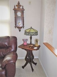 The clock is a West German reproduction. Very nice antique parlor table with castors. Arts & Crafts lamp.