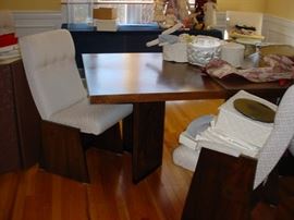This exquisite Mid Century teak dining table, plus two leaves, and matching wood and upholstered chairs