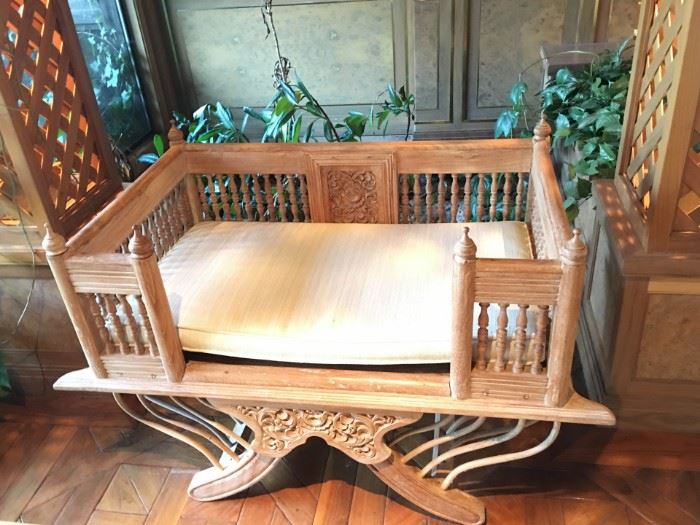 One of two carved wood gallery chairs with cushions.
